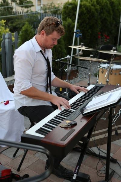 A man in a white shirt and tie is playing a keyboard