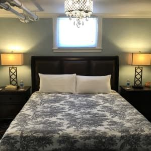 A bedroom with a bed , two lamps and a window.