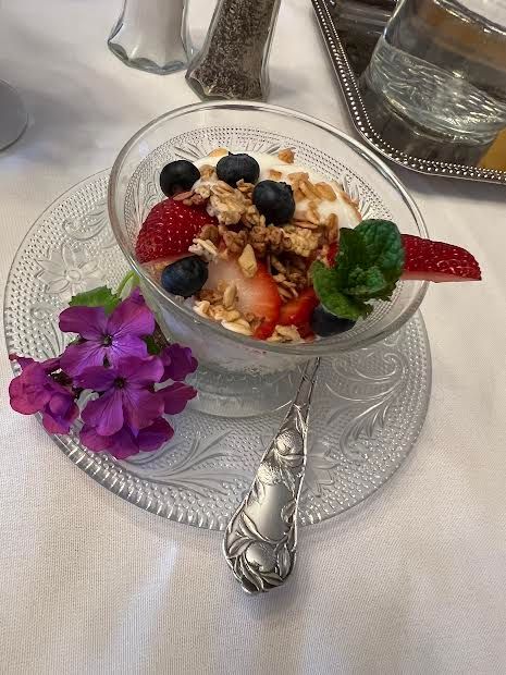 A bowl of yogurt with strawberries , blueberries and granola on a glass plate.