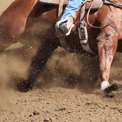 A person is riding a brown horse in the dirt.