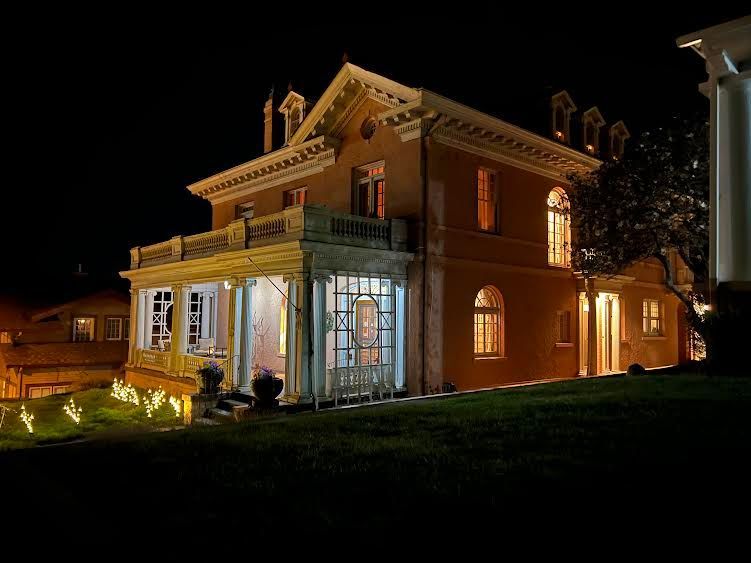 A large house with a lot of windows is lit up at night.