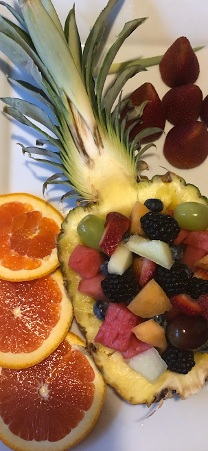 A pineapple filled with fruit and grapefruit slices on a plate.
