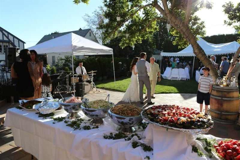 A bride and groom are standing in front of a buffet table filled with food.