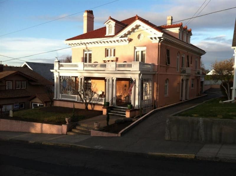 A large pink house with a red roof and white trim