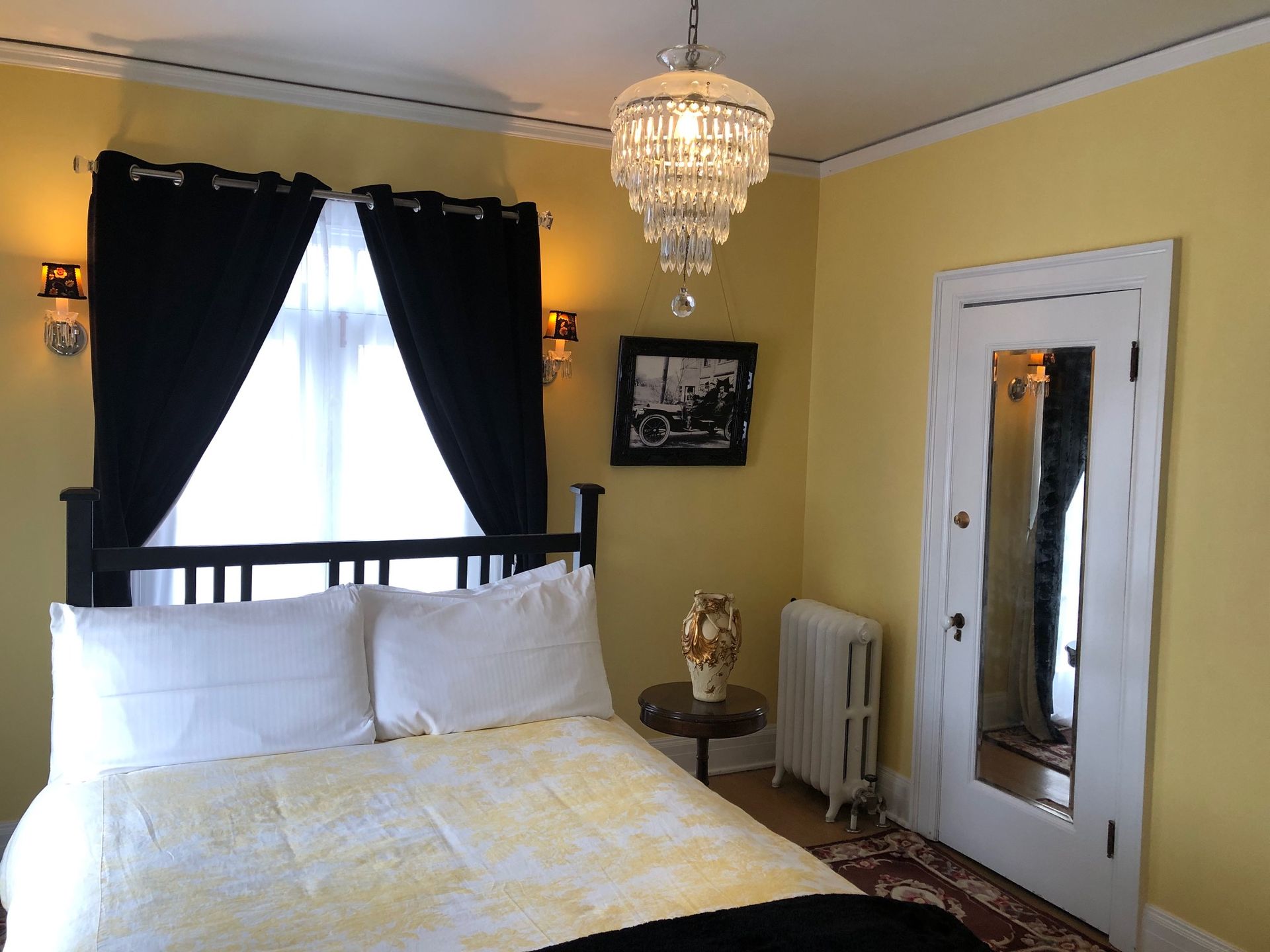A bedroom with a bed and a chandelier hanging from the ceiling