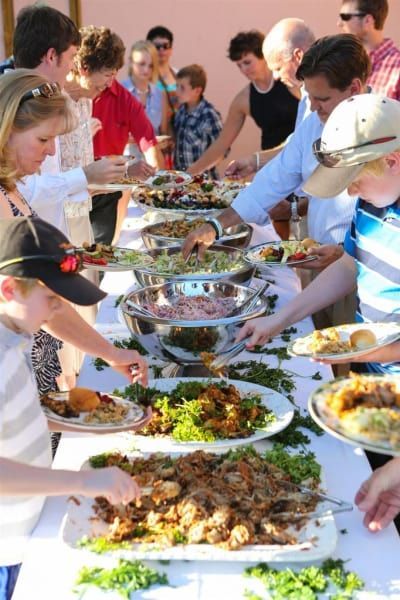 A group of people are standing around a table eating food