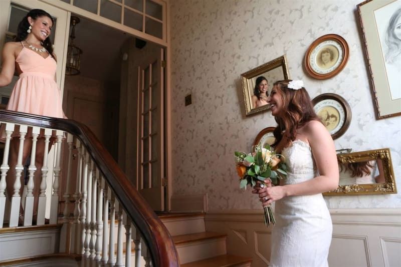 A bride and her bridesmaid are standing on a set of stairs.