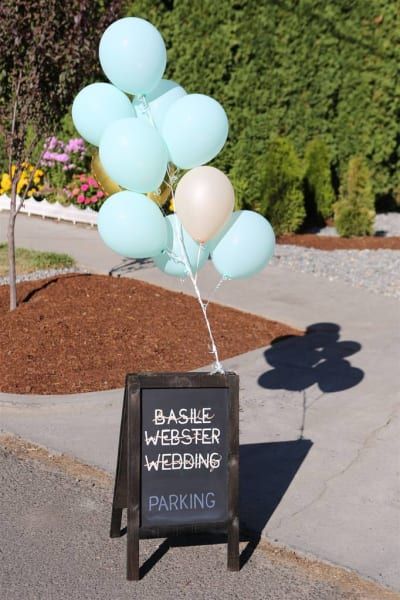 A bunch of balloons hanging from a sign that says basile webster wedding parking