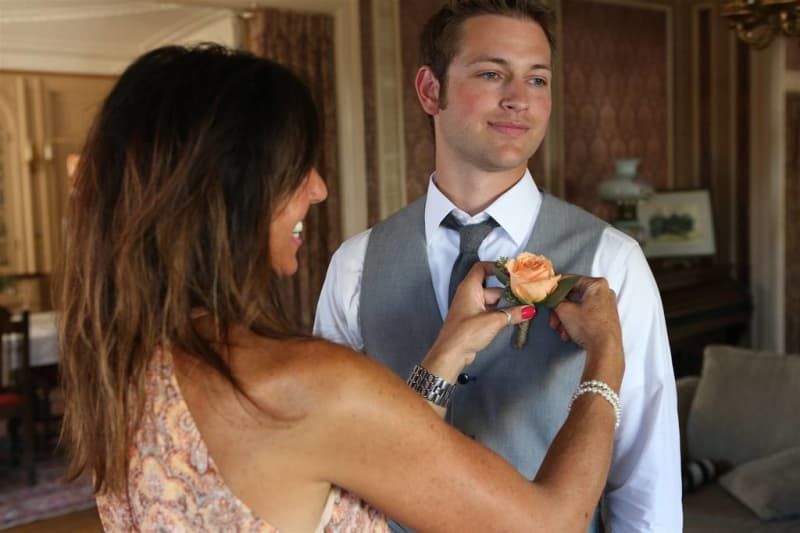 A woman is putting a flower on a man 's jacket.