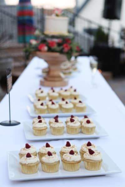Cupcakes on plates on a table with a cake in the background