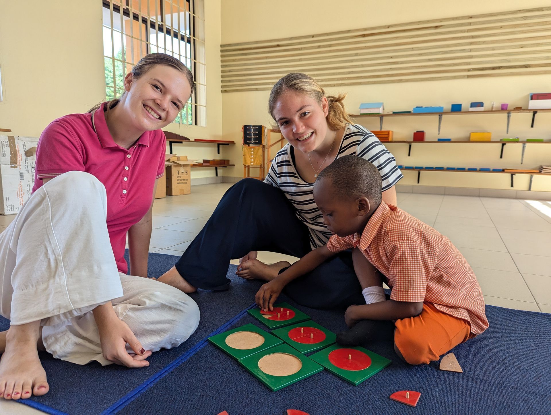 Sechs lächelnde Kinder sitzen im Freien um einen Teller mit Essen versammelt. Ein Junge hält den Teller.