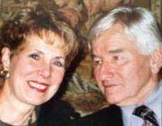 Junge Person mit geflochtenen Haaren lächelt, im Freien, weicher Hintergrund.