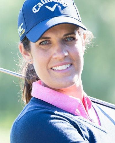 Junge Person mit geflochtenen Haaren lächelt, im Freien, weicher Hintergrund.