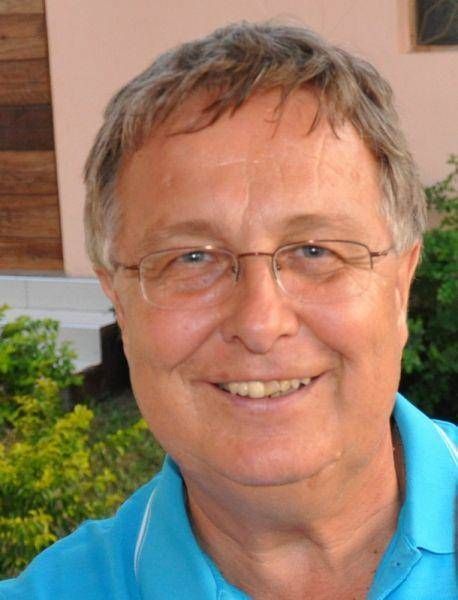 Junge Person mit geflochtenen Haaren lächelt, im Freien, weicher Hintergrund.