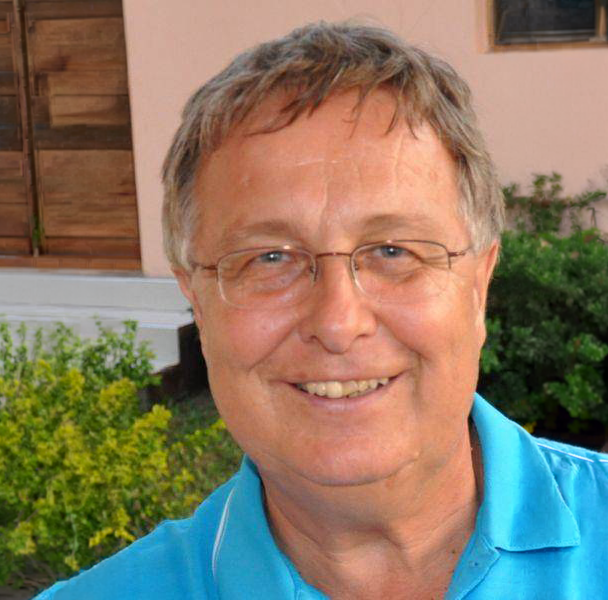 Junge Person mit geflochtenen Haaren lächelt, im Freien, weicher Hintergrund.