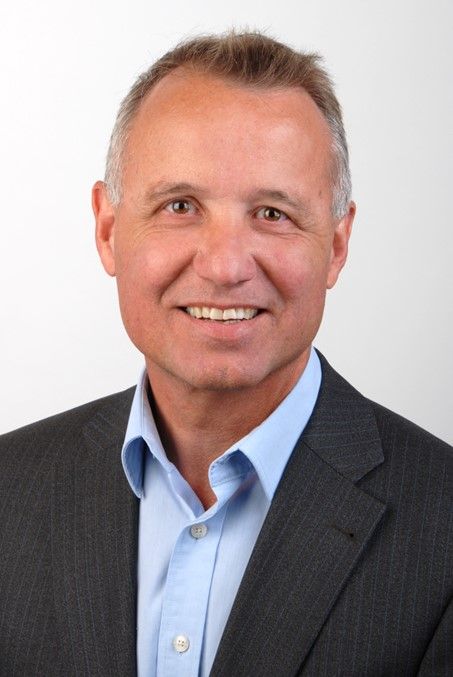 Junge Person mit geflochtenen Haaren lächelt, im Freien, weicher Hintergrund.