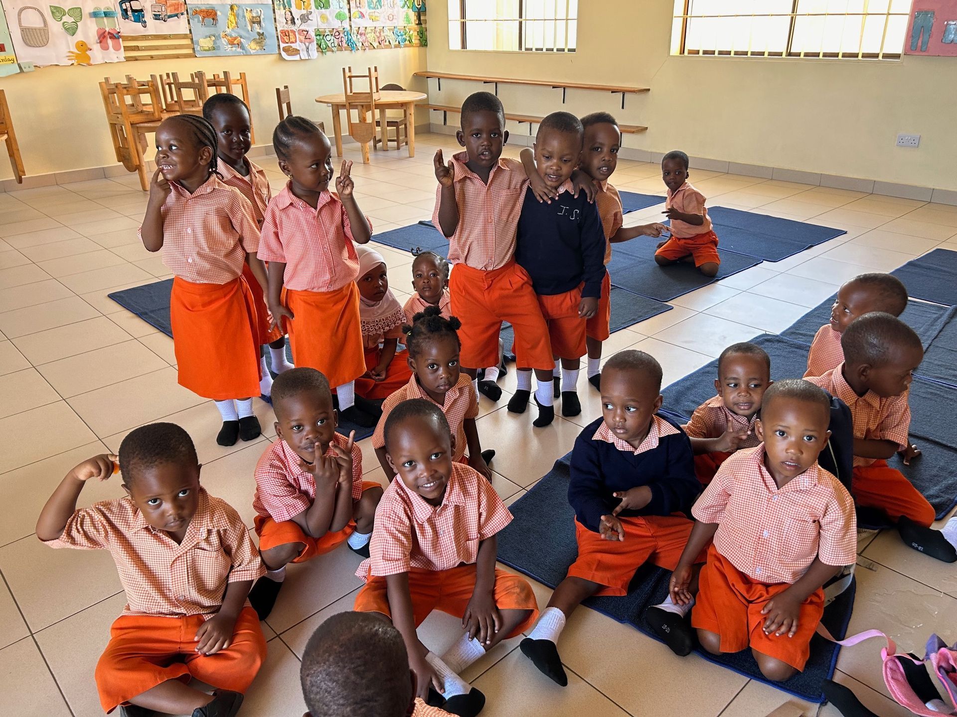 Zwei Kinder in Schuluniformen fahren in einem Fahrzeug und blicken nach vorn. Sonnenlicht strömt herein.