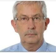 Junge Person mit geflochtenen Haaren lächelt, im Freien, weicher Hintergrund.