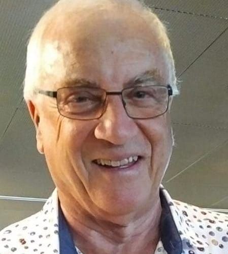 Junge Person mit geflochtenen Haaren lächelt, im Freien, weicher Hintergrund.