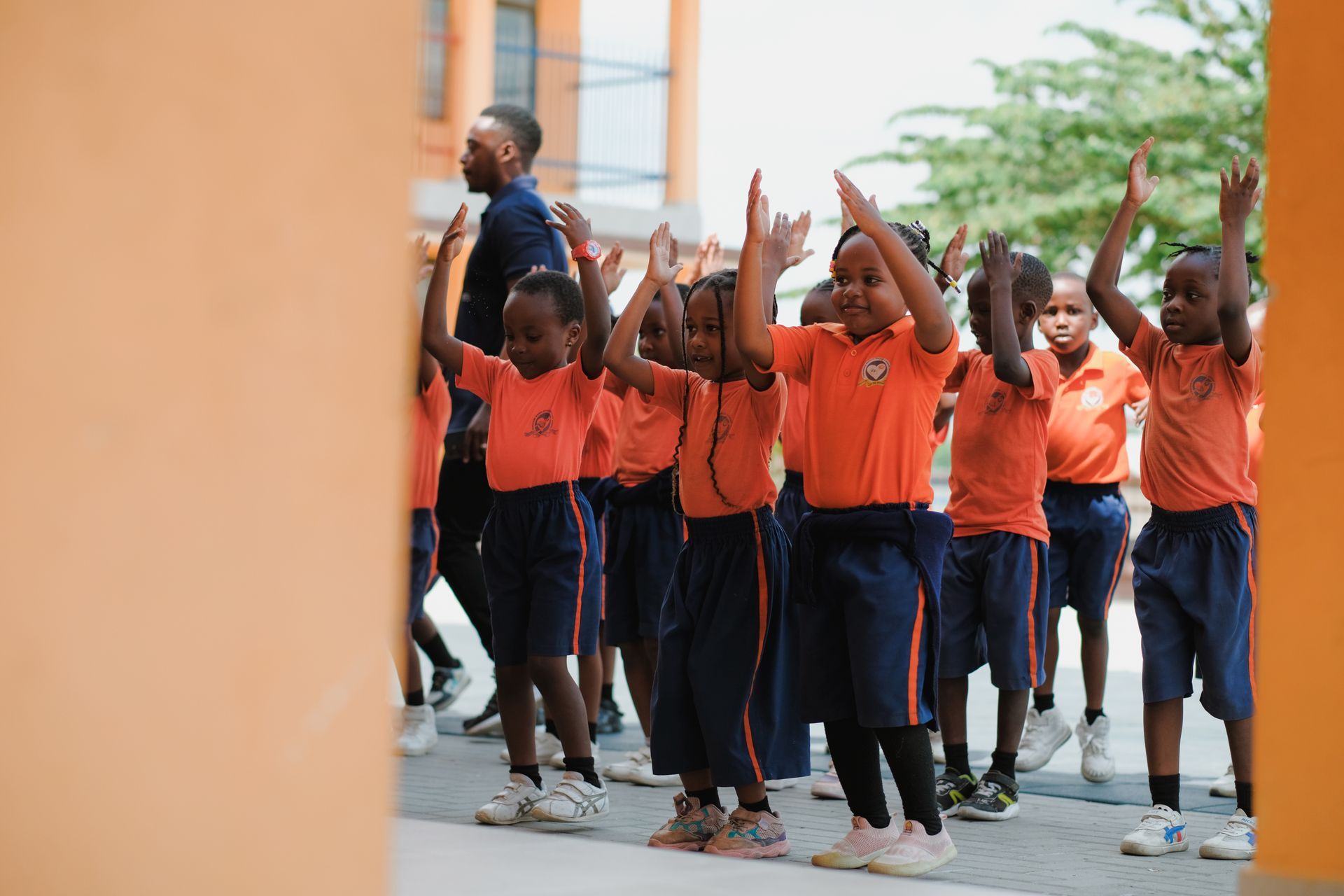 Sechs lächelnde Kinder sitzen im Freien um einen Teller mit Essen versammelt. Ein Junge hält den Teller.