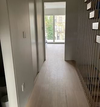 A hallway with hardwood floors and a staircase leading to a living room.