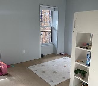 A bedroom with a bunk bed , a rug , a shelf and a window.