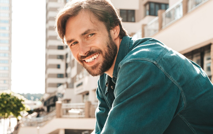 Woman holding a measuring tape and a blender filled with greens, smiling. Kitchen setting.