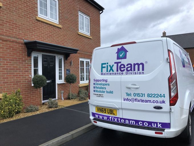 A fix team van is parked in front of a brick house