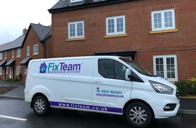 A fix team van is parked in front of a brick building