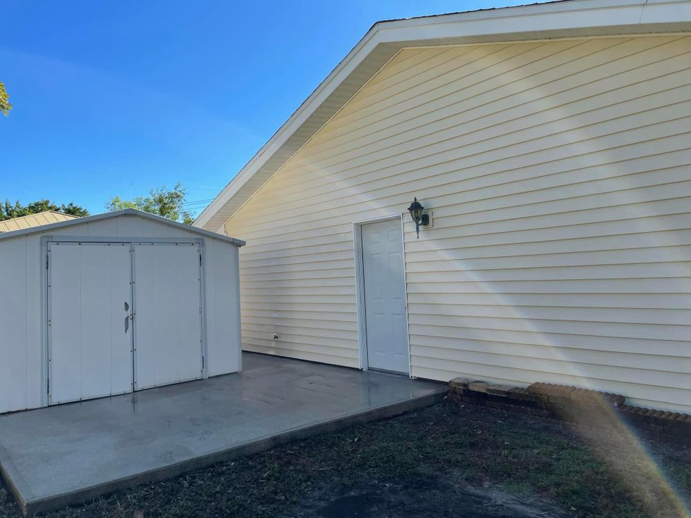 A white shed is in the backyard of a house.