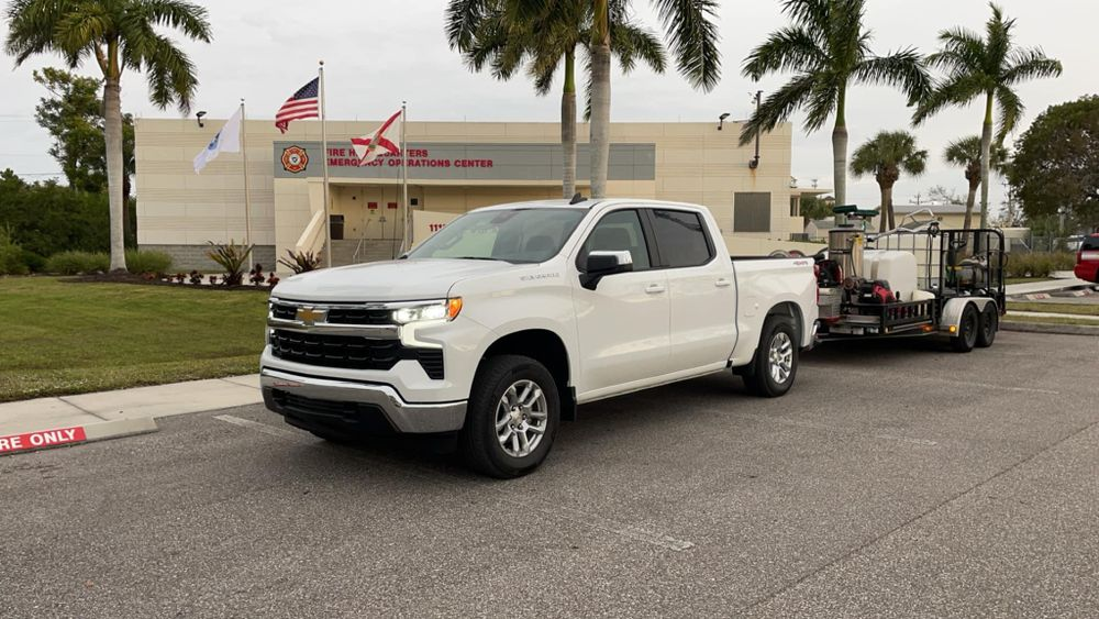 A white truck with a trailer attached to it is parked in front of a building.