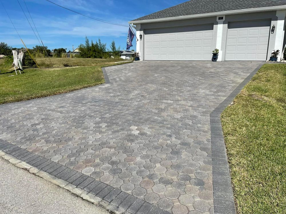 A brick driveway leading to a house with a garage.