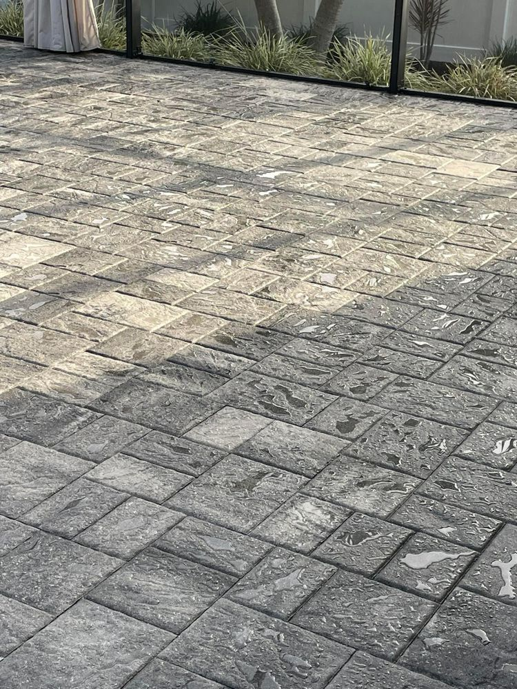 A close up of a brick driveway with a fence in the background.
