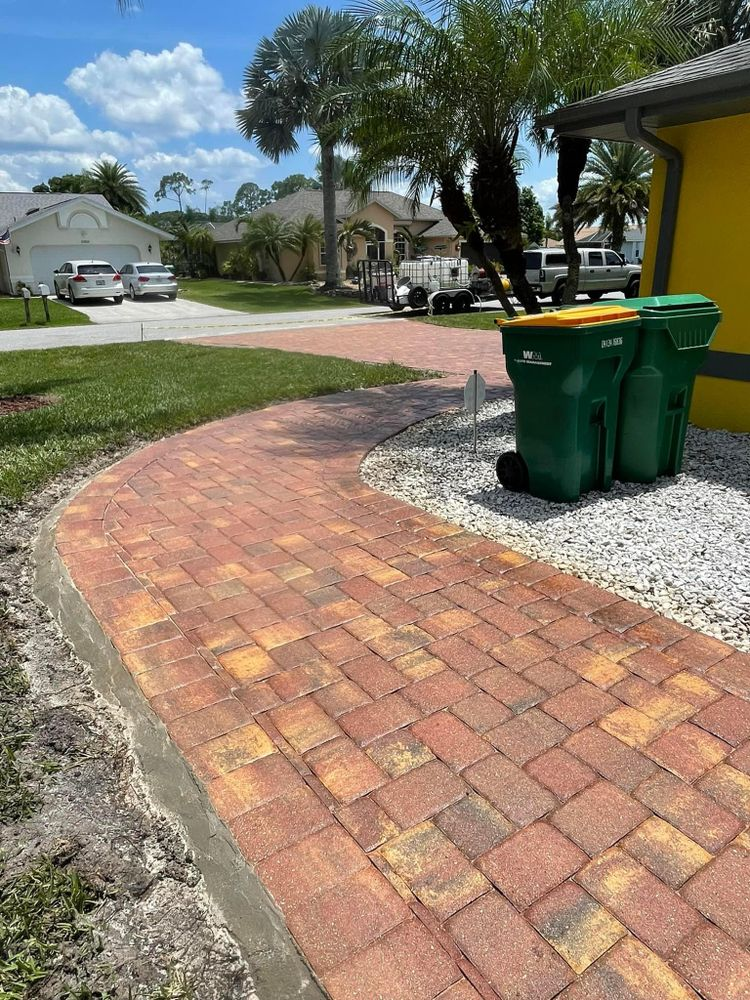 A brick walkway with two green trash cans on the side of it.