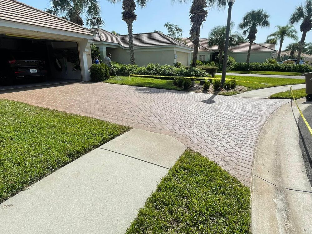 A car is parked in a garage next to a brick driveway.