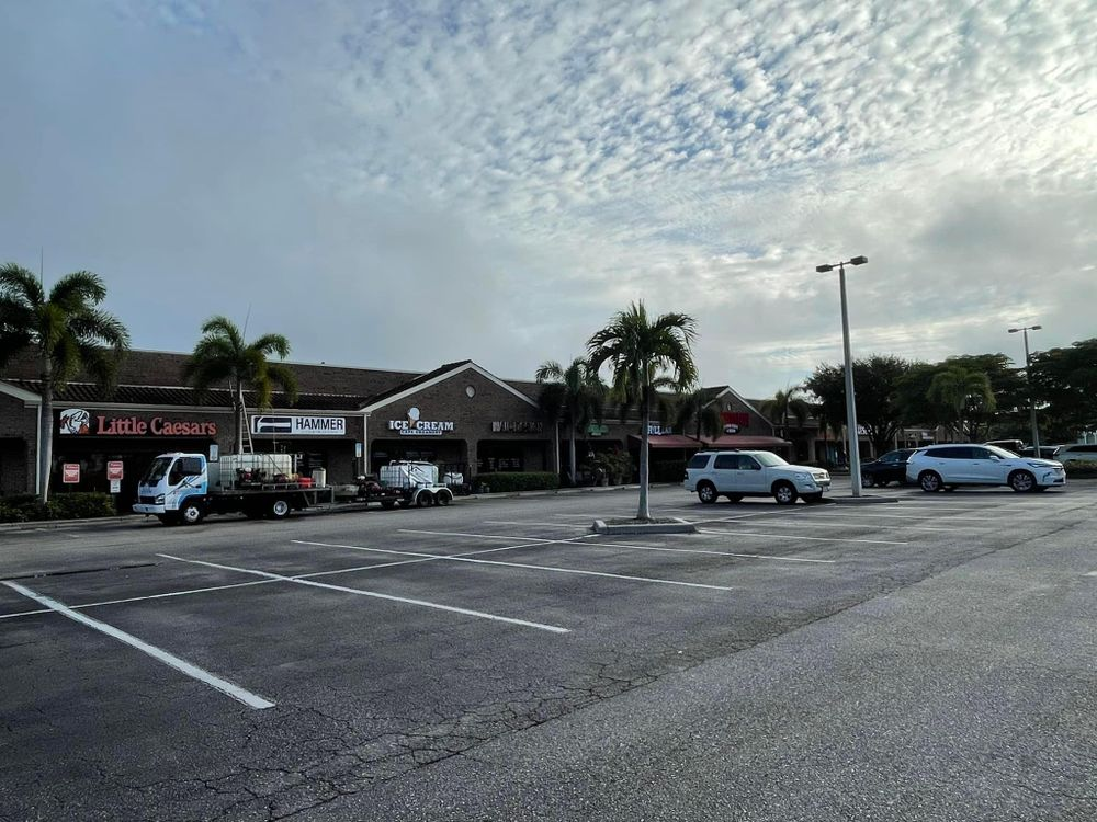 A parking lot with cars parked in front of a little caesars restaurant.