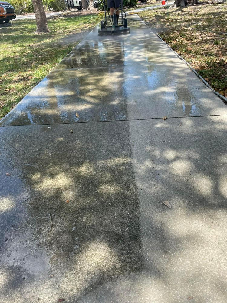 A person is cleaning a sidewalk with a machine.