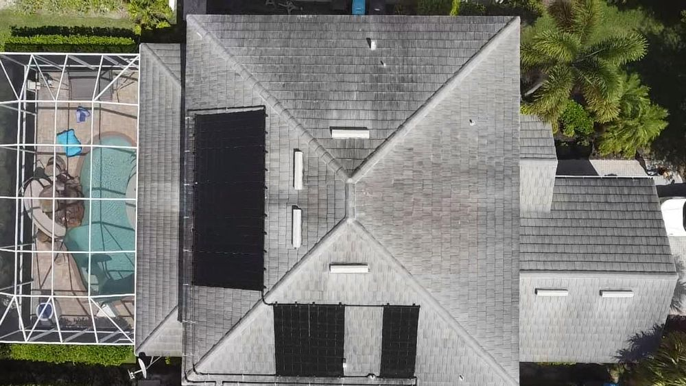 An aerial view of a house with a pool and solar panels on the roof.