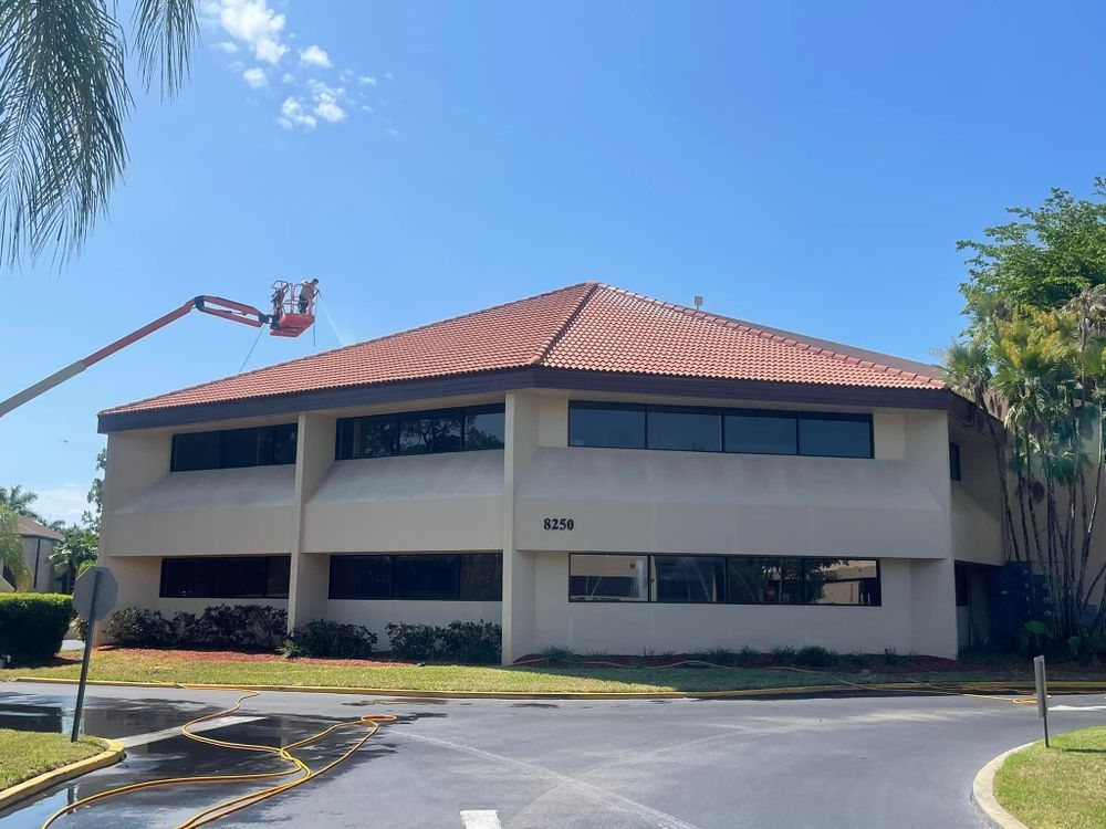 A large building with a red tile roof is being cleaned by a crane.