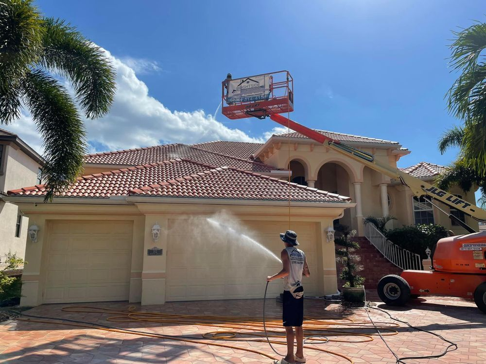 A man is spraying water on the roof of a house.