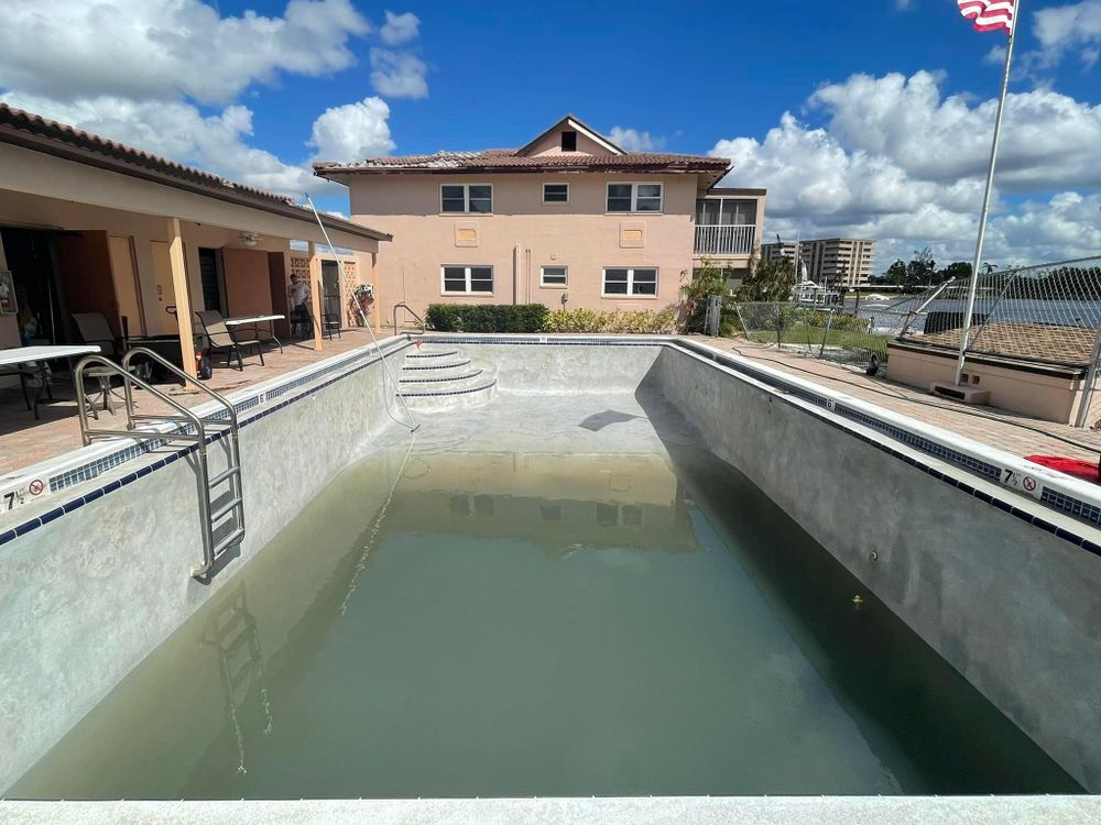 An empty swimming pool with a house in the background