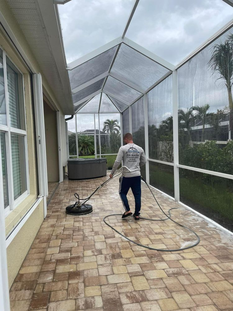A man is cleaning a brick patio with a pressure washer.