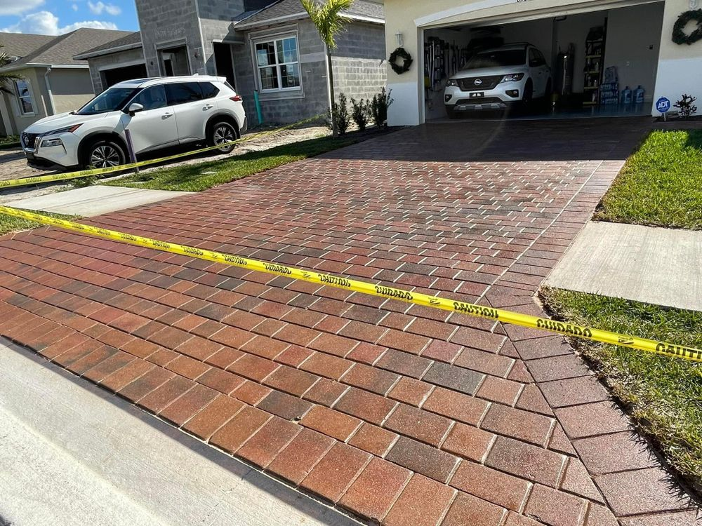 A white suv is parked in a driveway next to a brick driveway.