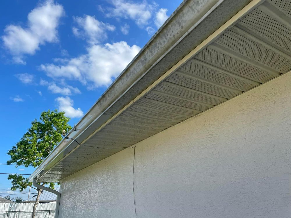 A white house with a gutter on the side of it and a blue sky in the background.