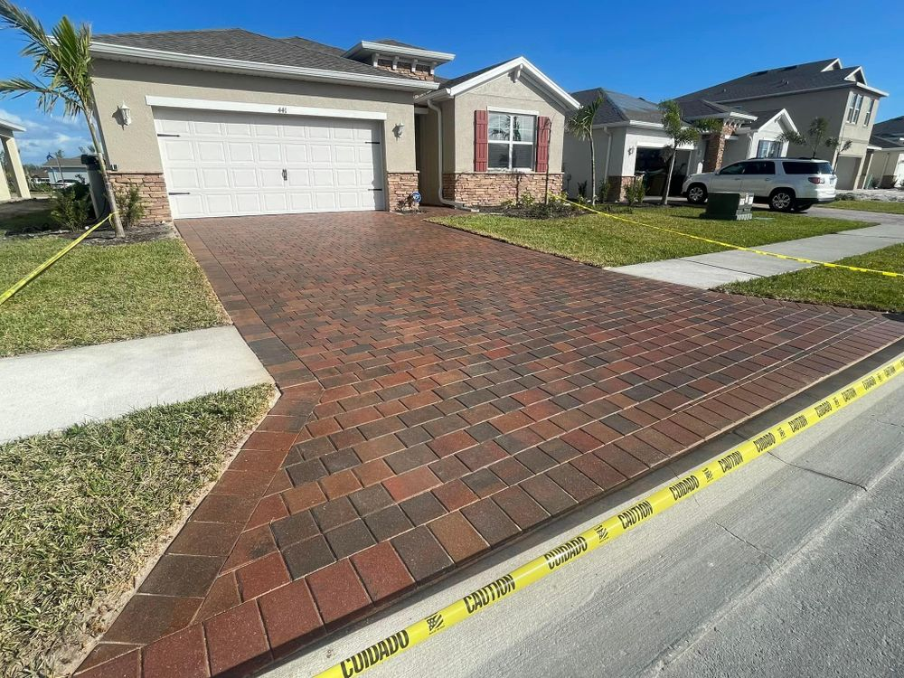 A brick driveway leading to a house with a white garage door.