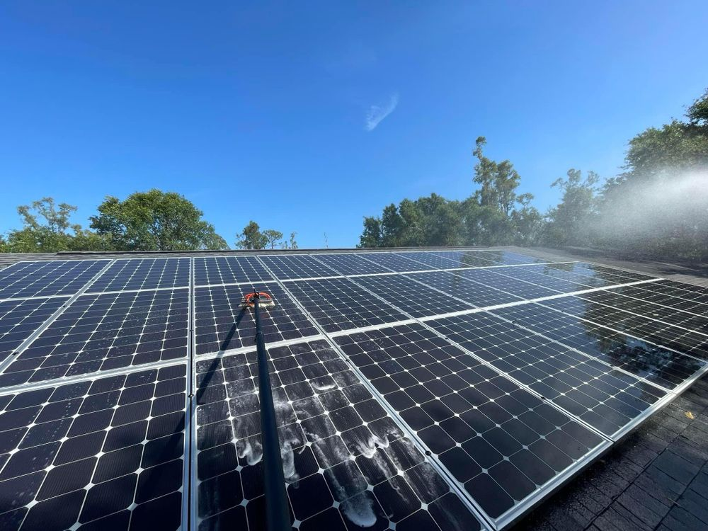 A row of solar panels are being cleaned with a hose.