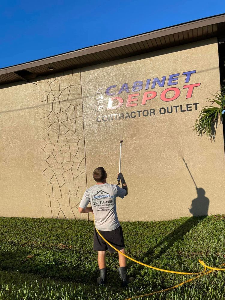 A man is cleaning the side of a building with a hose.