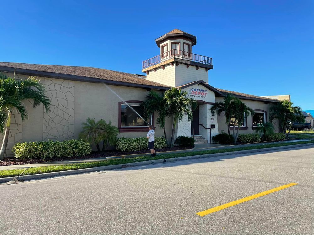 A man is cleaning the windows of a building with a hose.