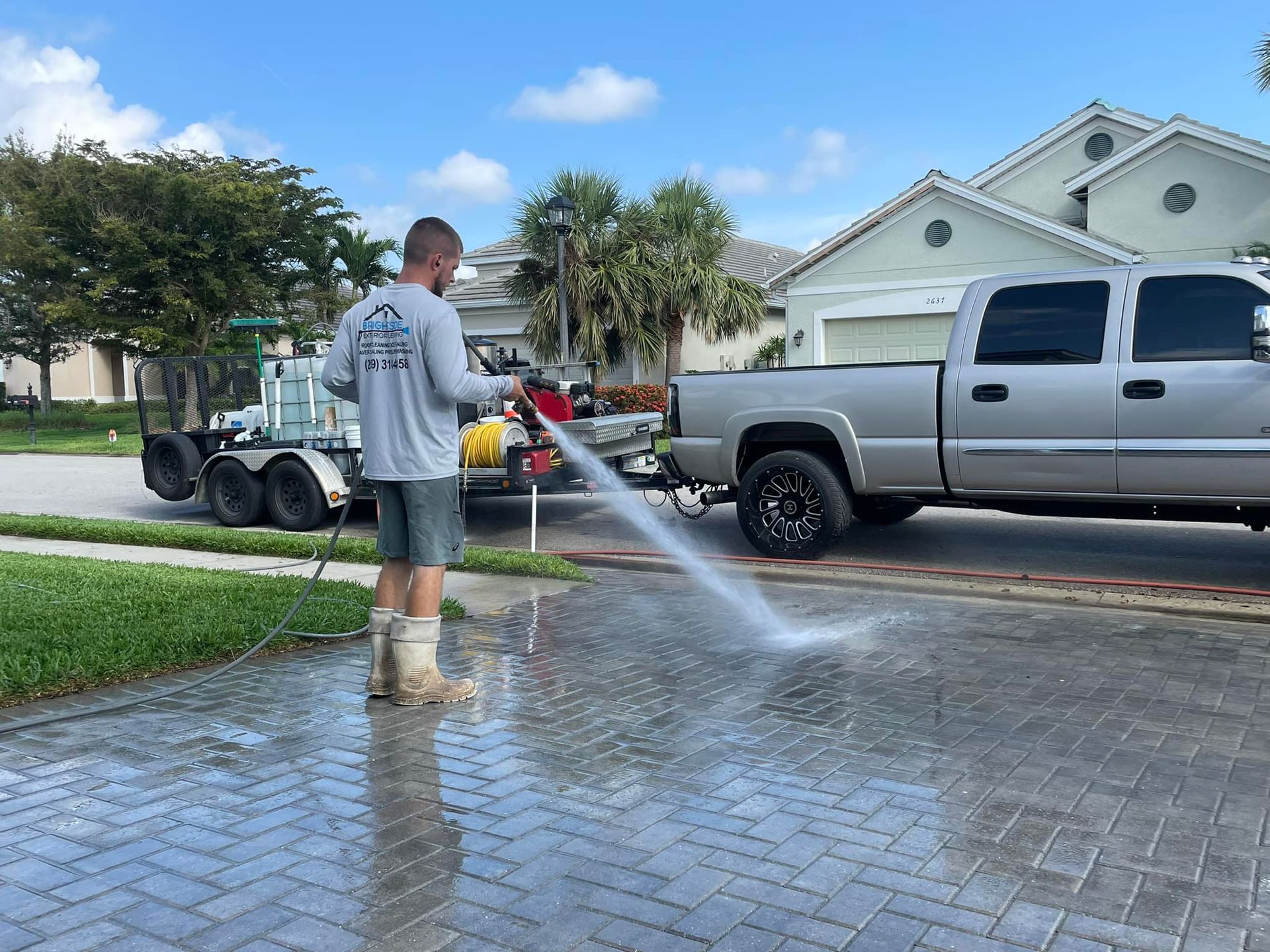 A man is using a high pressure washer to clean a driveway.