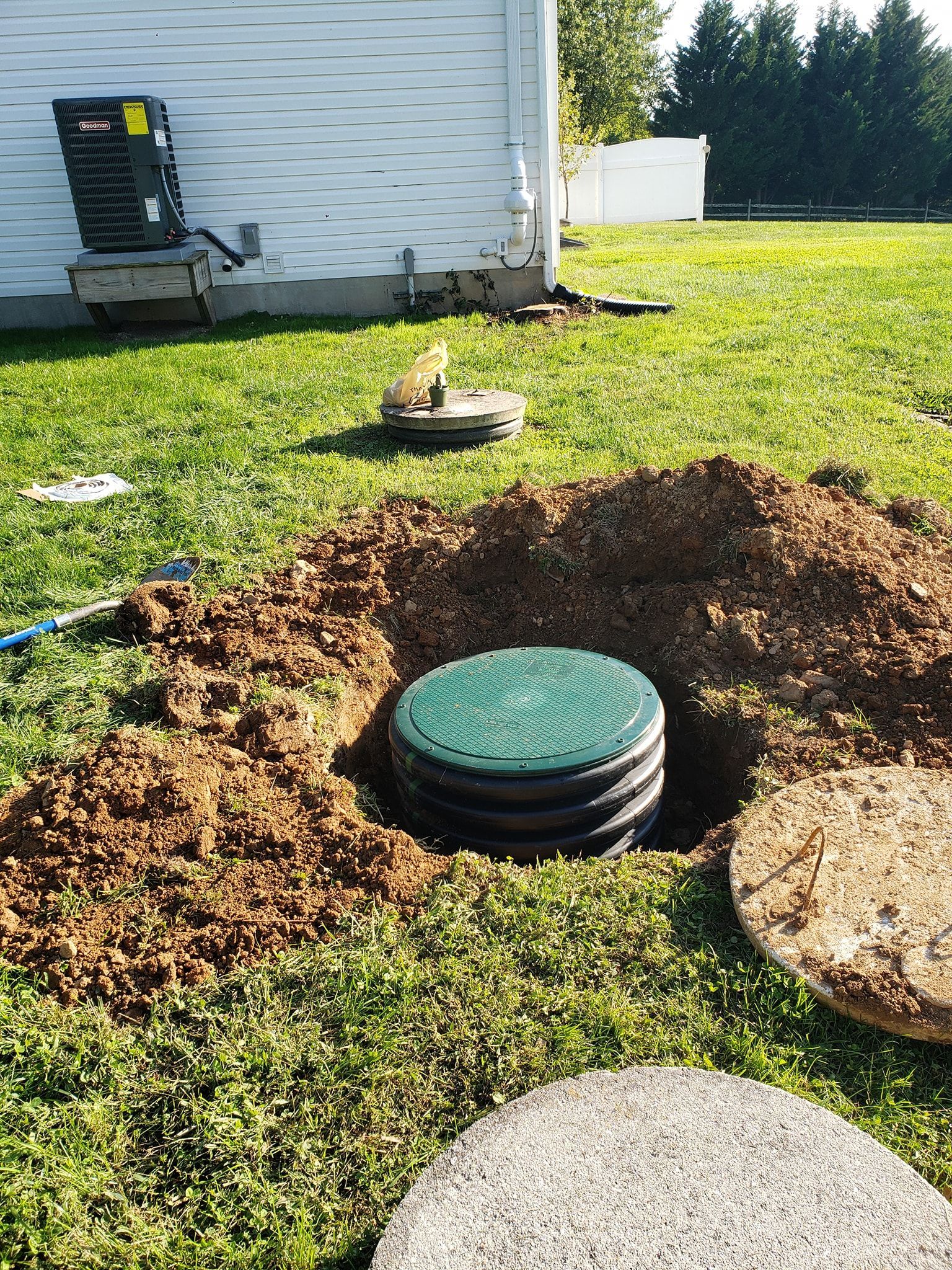 Three black plastic septic tanks installed in a dirt excavation with green lids and orange pipes. Three black plastic septic tanks installed in a dirt excavation with green lids and orange pipes.